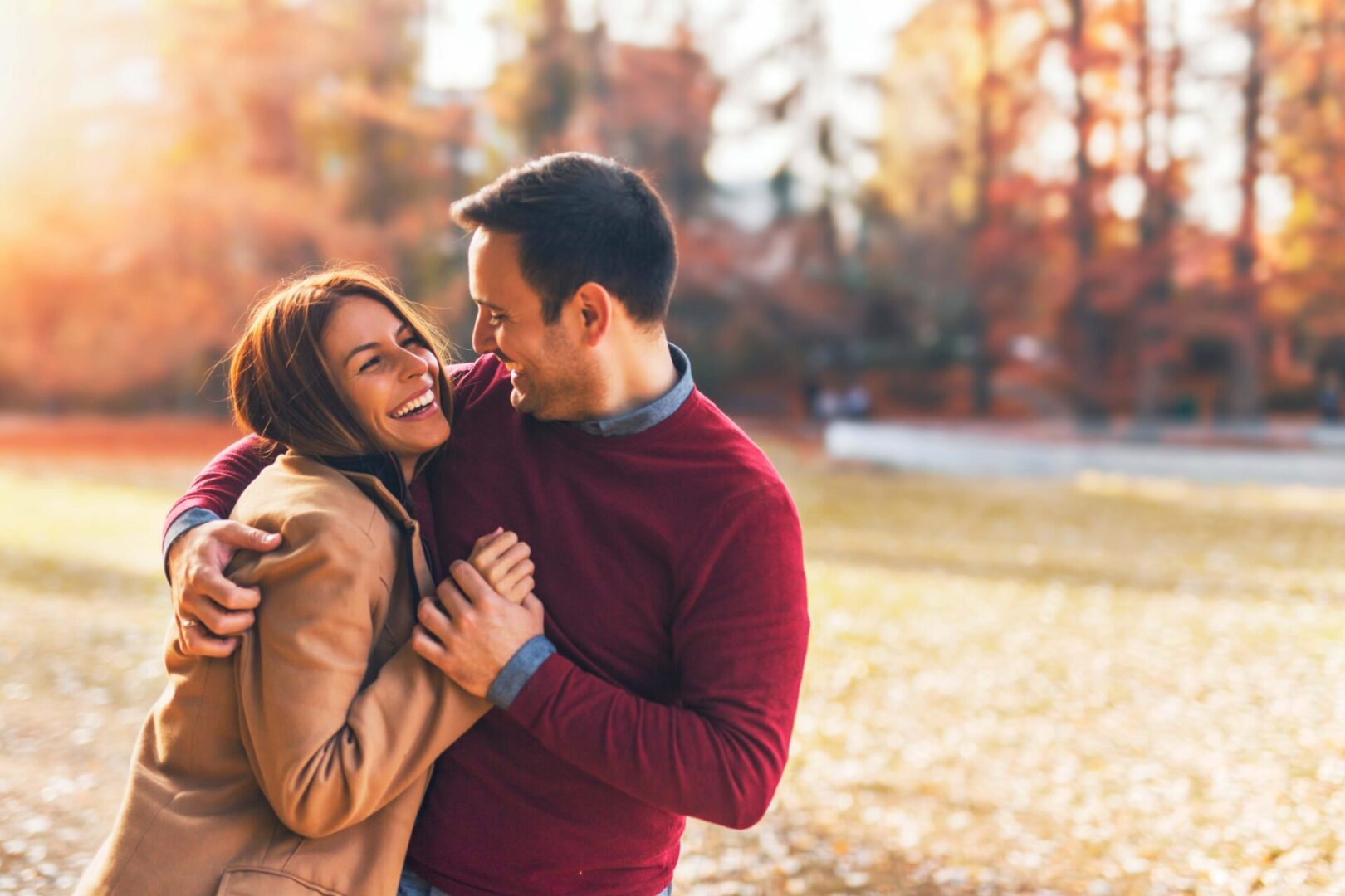 GettyImages-1181815683 A couple, radiant and embracing in a park during autumn, find joy among the colorful leaves, reminiscent of the closeness nurtured at relationship retreats.